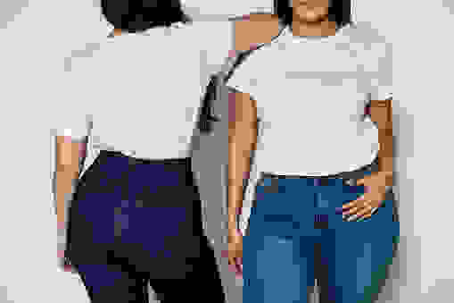 Cropped shot of two women standing in opposite directions on white background. Women wearing white t-shirt and blue denim jeans.