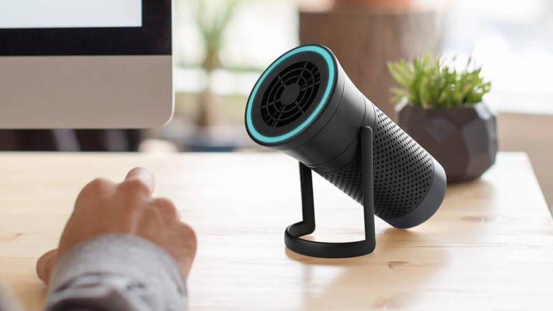 The Wynd portable air purifier on a desk next to a person's hand