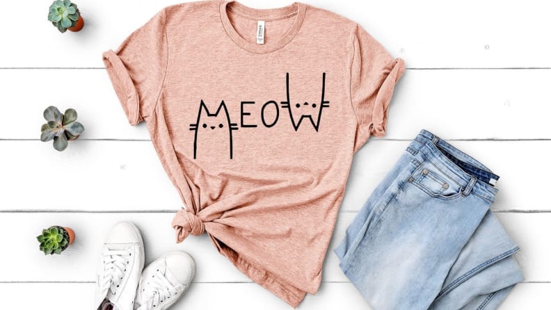 a pink t-shirt that says meow on a white background
