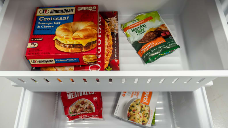 A close-up of a fridge's freezer drawer, with both its main bit and upper drawer full of frozen foods.