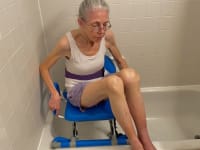 On left, elderly woman sitting in shower chair. On right, shower chair.