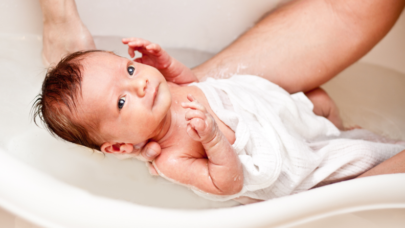 Small baby bathing in a shallow tub