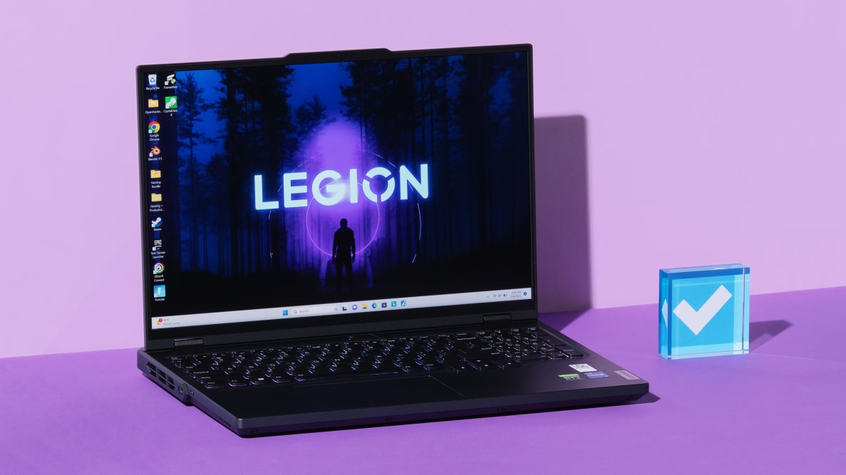 Black Lenovo Legion Pro 5i Gen 8 gaming laptop opened with desktop screensaver on screen next to blue acrylic paperweight in the middle of purple setting.