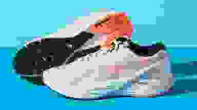 A pair of white and orange running shoes against a blue backdrop.