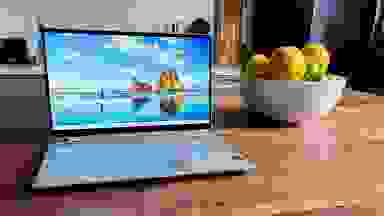 An HP Spectre laptop sitting next to a bowl of fake fruit.
