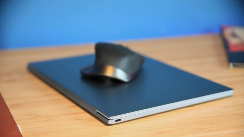 A closed Dell XPS 13 9315 laptop with a wireless mouse resting atop it.