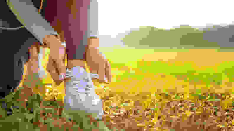 A woman tying her shoes in a field