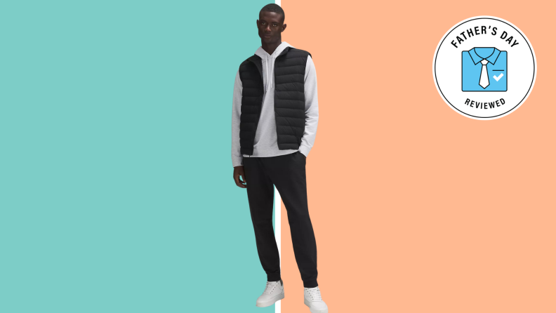 A Black man stands in a fashionable lululemon outfit with black pants and a black vest and a white shirt