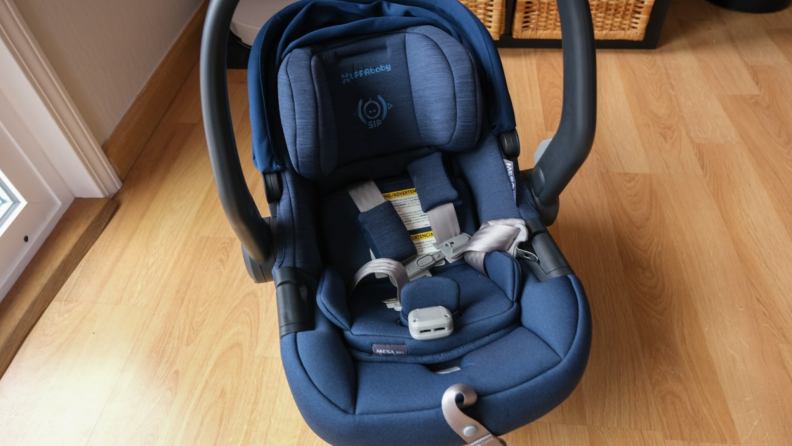 The Uppababy Mesa Max car seat in navy blue on top of hardwood floor.