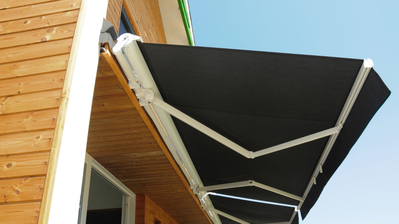 A retractable awning is attached to the side of a house