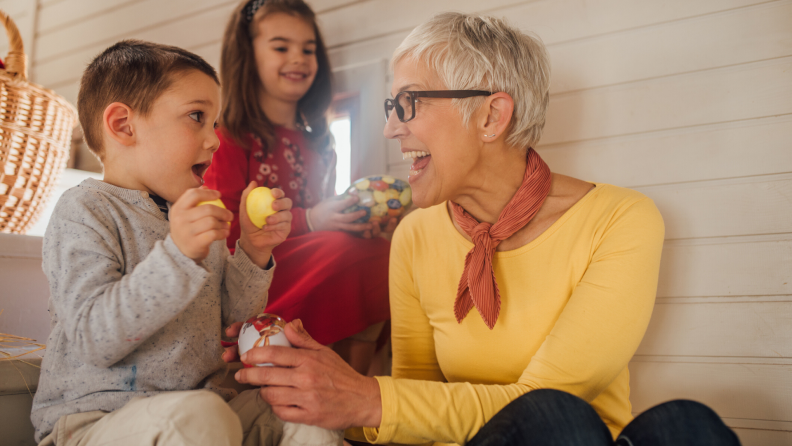 A boy and girl show off their egg hunt findings to their grandmother