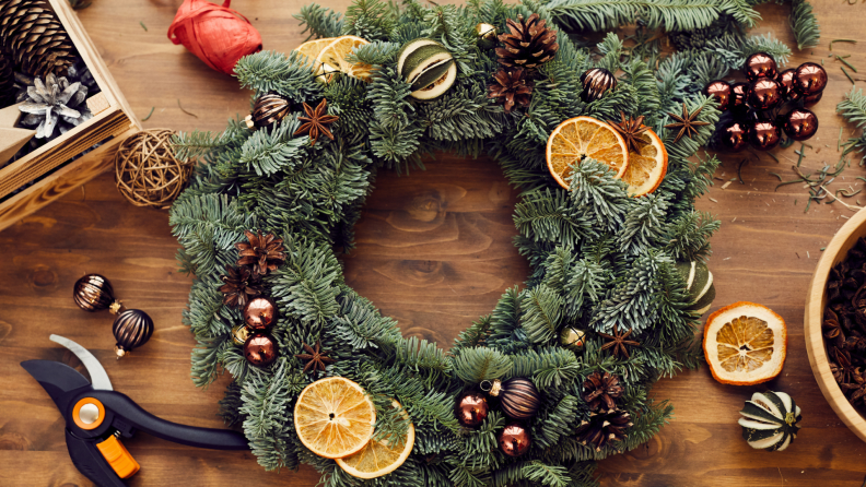 Dried orange slices on top of an evergreen wreath with pinecones and small metallic ornaments