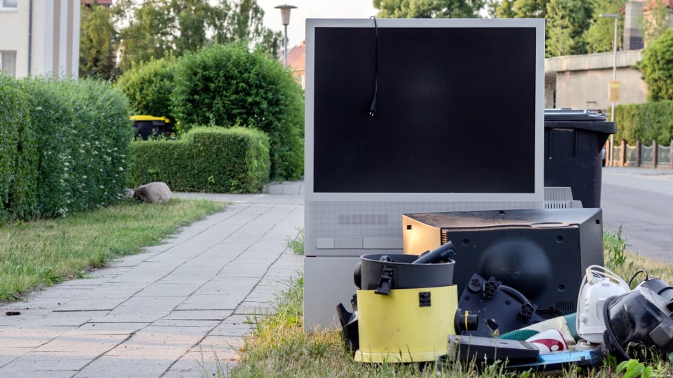 A TV sitting in a trash pile on the curb