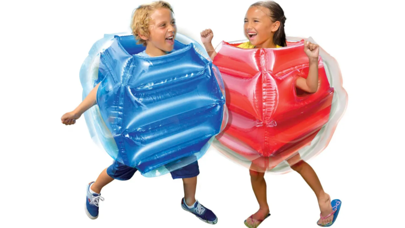 Two children bump into each other wearing inflatable suits.