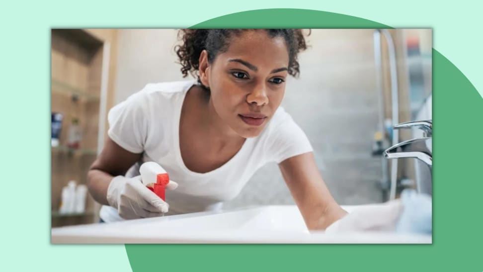 Person wearing white rubber gloves to clean sink surface in bathroom.