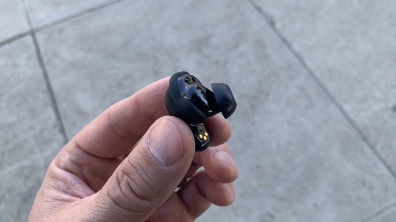 Close-up shot of a hand holding a Bose QuietComfort II earbud.