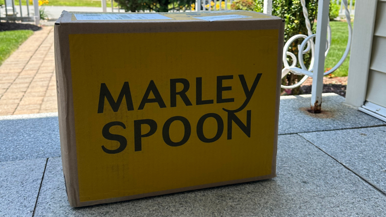 A photo of a Marley Spoon shipping box on a porch outside.