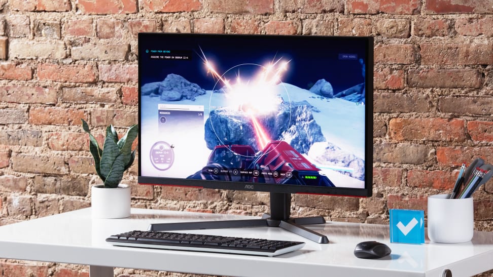 The AOC Q27G3XMN gaming monitor on a white desk, with desk supplies around it.