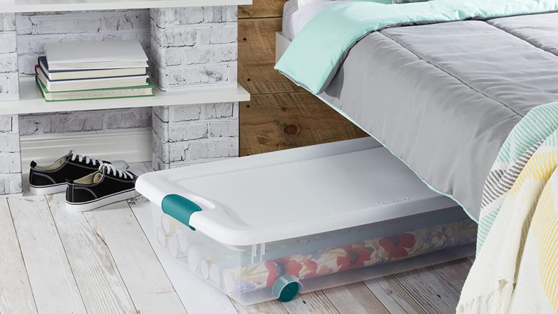 A plastic tub sliding out from under a bed.