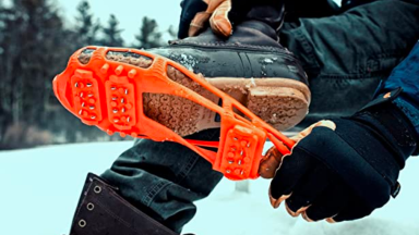 一个人将防滑钉放在外面的冬季靴子上。