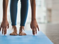A woman touching her toes on a yoga mat.