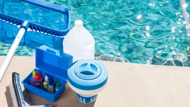 Cleaning materials for pool maintenance sitting on the edge of a pool.