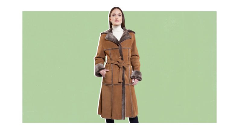 A model wearing a long brown shearling trench.