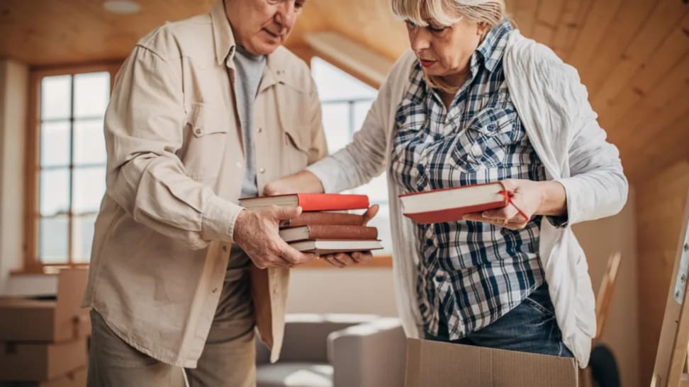 Senior couple organizing books into box at home.