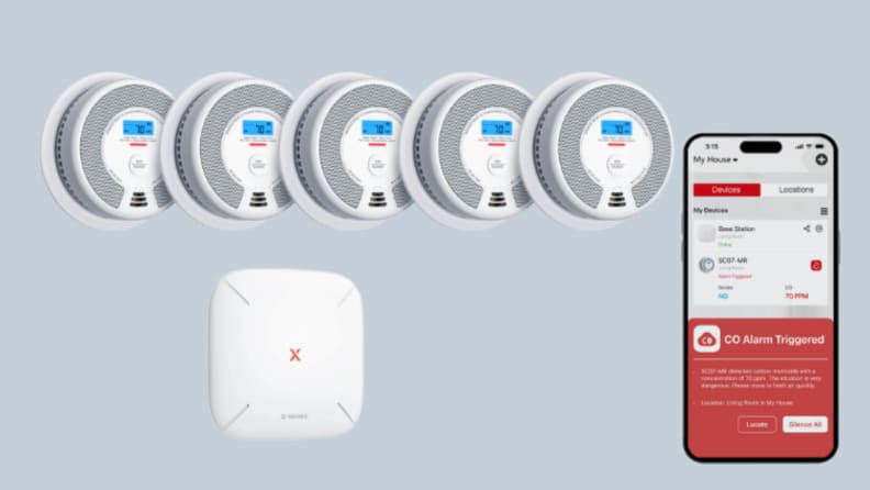 5 smoke detectors, a base, and a phone sit on a gray background