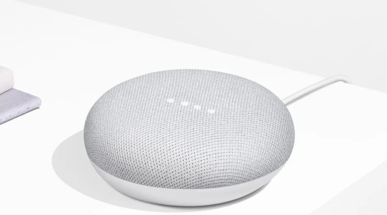 A Google Home Mini smart speaker sits on a countertop.