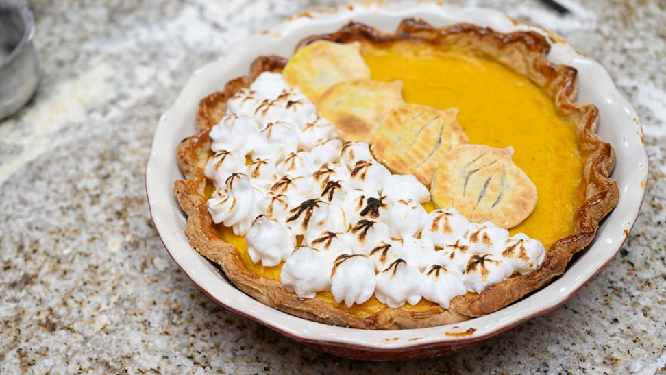 A pumpkin pie with scorched meringue and pumpkin-shaped cookies on top.