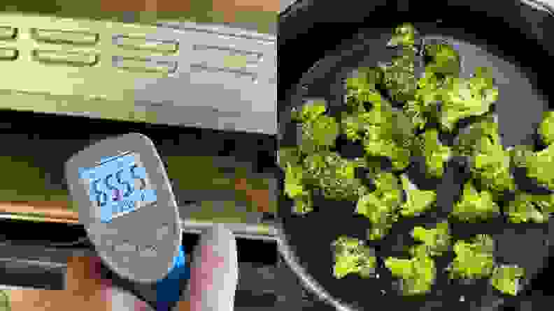 A person holding thermometer next to a pan filled with cooked broccoli on top of a stove.