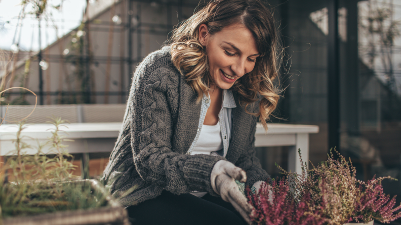 Person smiling while planting flowers outdoors.