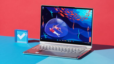 A silver laptop open and powered on against a blue and red backdrop.