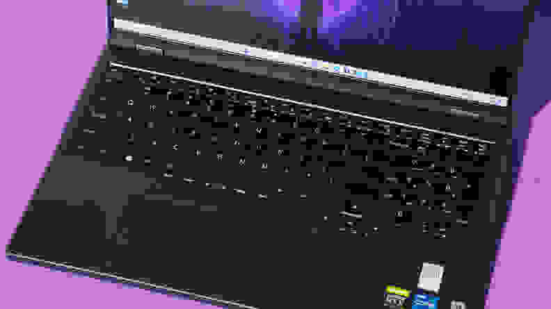 Close-up of the black keyboard and trackpad on the Lenovo Legion Pro 5i-Gen 8 gaming laptop with laptop's screen display turned on in front of purple background.
