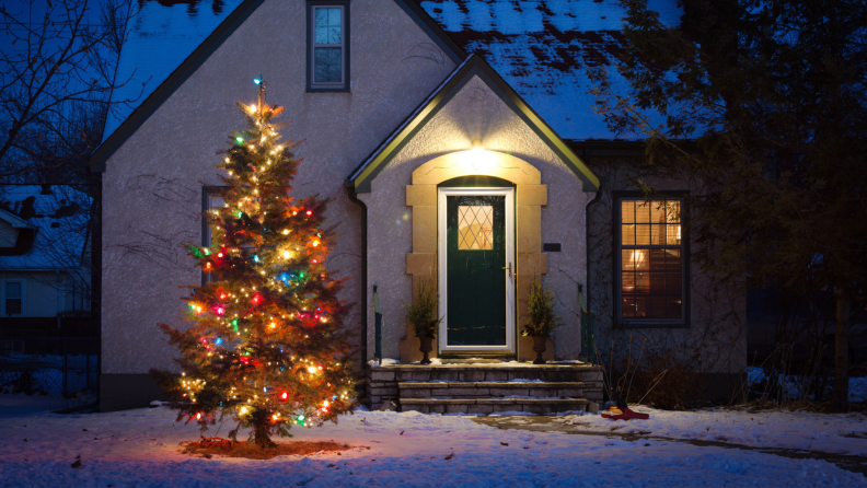 Christmas tree with string lights in front yard of home.