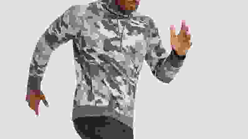 A man wearing a camo sweatshirt, pumping his arms.