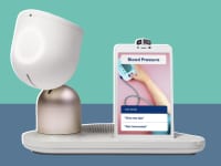 ElliQ robot stationed next to a tablet that has blood pressure results on the tablet screen.