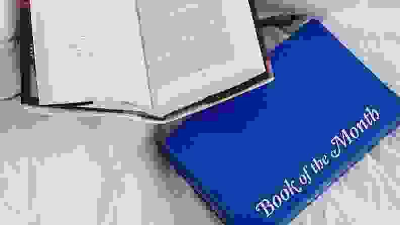 A blue box and open book on a bed