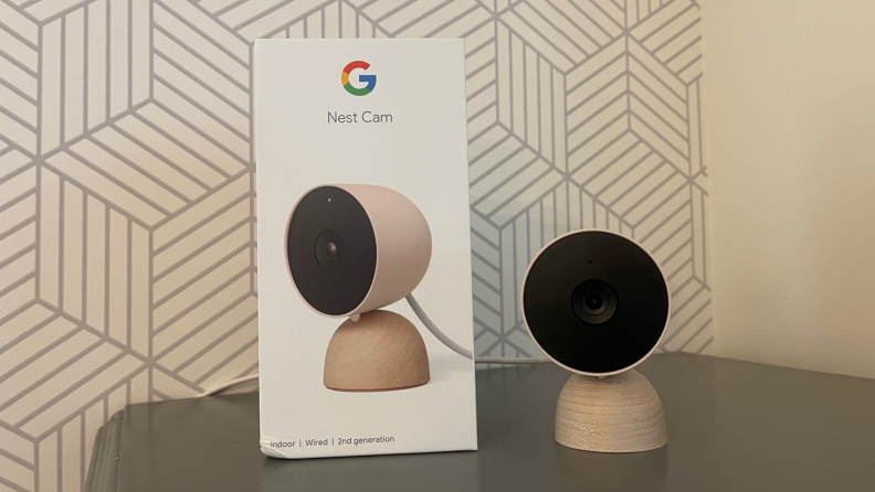 The Nest Cam (indoor, wired) next to the product's packaging.