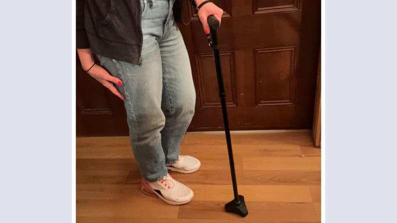 Person standing next to the HurryCane Freedom Edition while firmly grasping the handle.