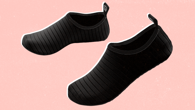 A pair of black wading shoes against a pink background.