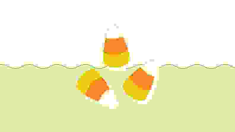 Three pieces of candy corn on a green and beige background