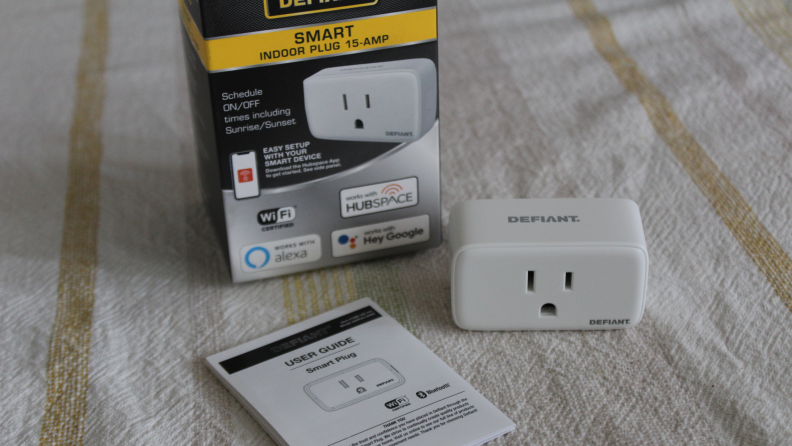 Defiant Smart Plug outside of box packaging next to instructions on tabletop.