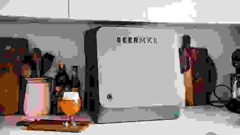 An automated beer brewing device sits on a kitchen counter.