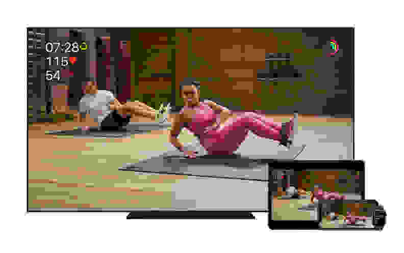 A Apple Fitness+ instructor leads people through a core workout, shown on a TV, iPad and, iPhone