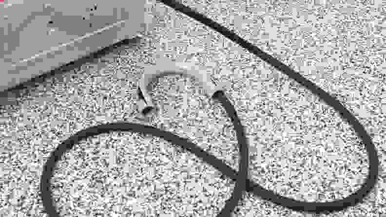 A close-up of a compact dryer's drainage hose. It's made of black rubber and ends in a gray plastic U-shaped piece.