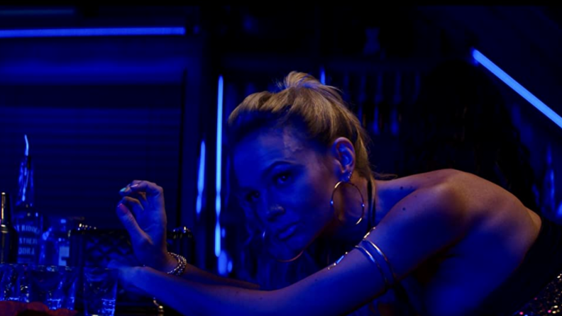 A still from the film Promising Young Woman featuring Carey Mulligan in blue and pink lighting in a club.