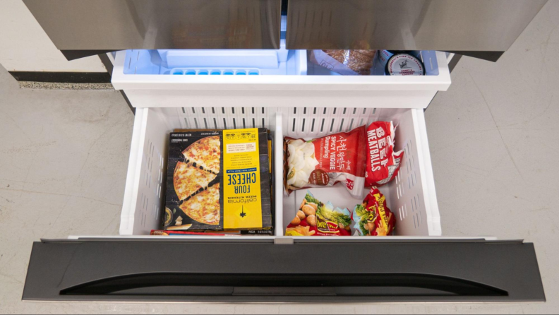 A view from above the freezer drawer, peering down into it. The main bin has a few frozen foods in it.