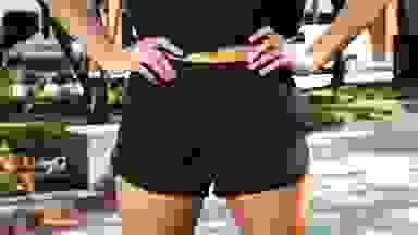 A person poses wearing a pair of 3-inch black running shorts outside.